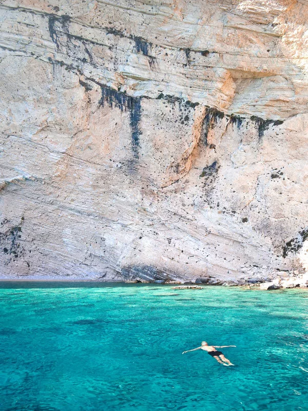swimming-in-turquoise-waters-near-a-steep-rock