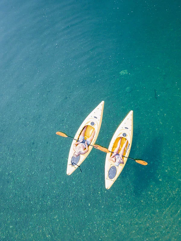 sea-kayak-two-kayaks-in-water-with-people-sunbathing-on-top